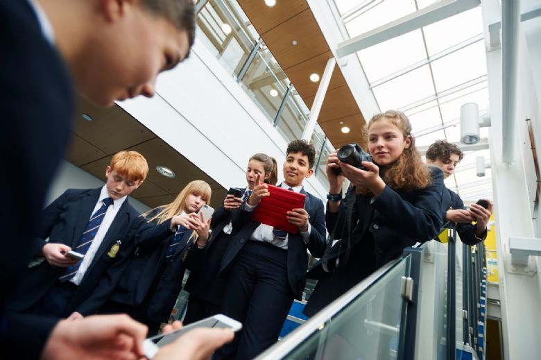 Group of students on stairs with phones, ipads and cameras, taking pictures