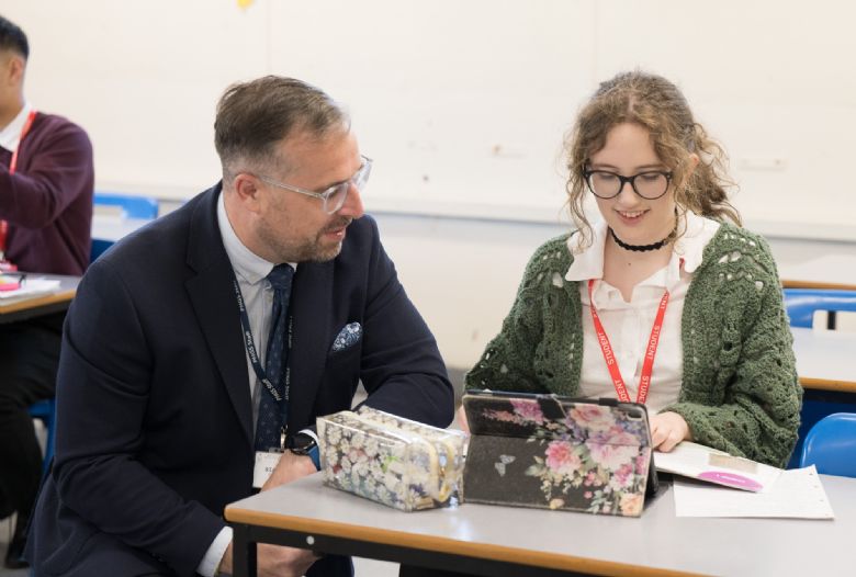 Students working with teacher, talking and smiling