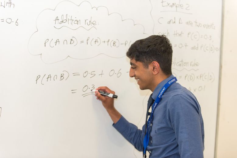 A level student working on equations on classroom whiteboard