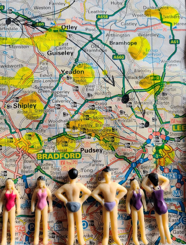 A map with highlighted towns on and plastic figures looking at it