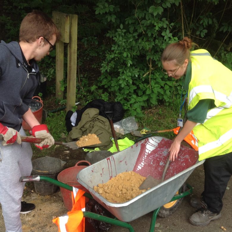 Student volunteering on Timanyane Day, digging with wheelbarrow