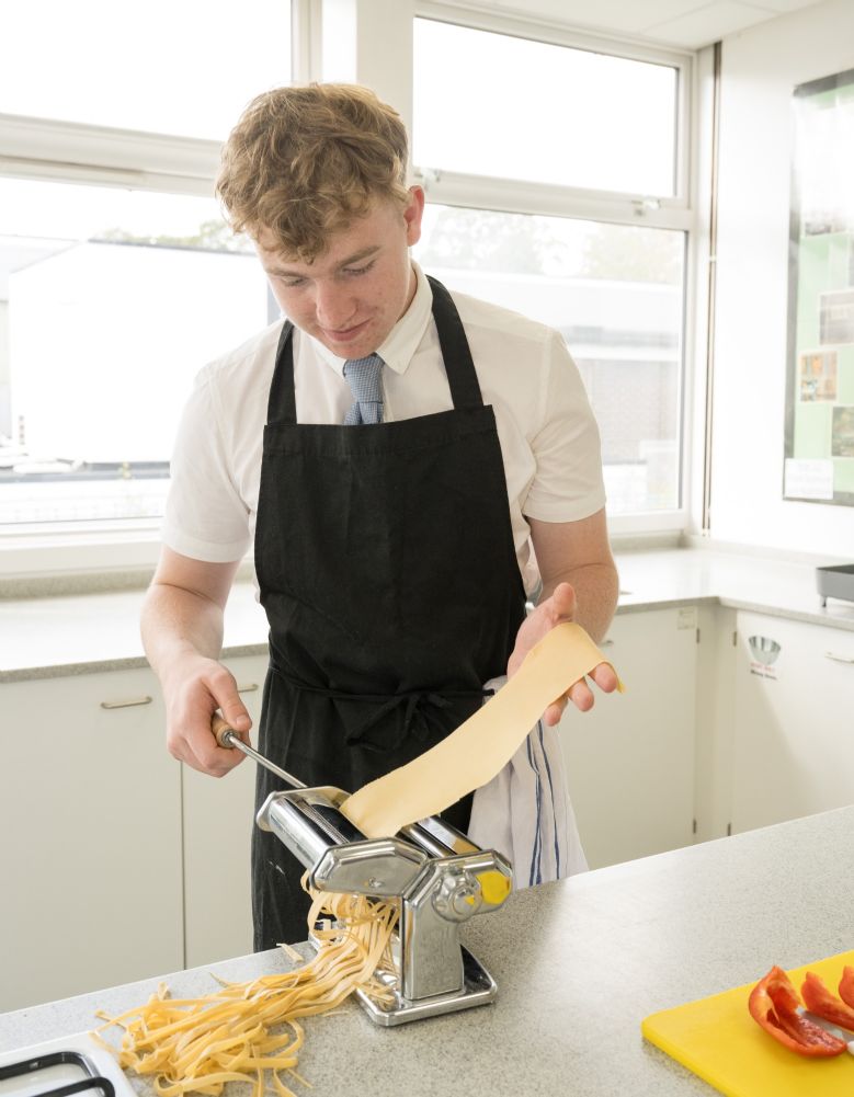 Boy making fresh pasta with machine